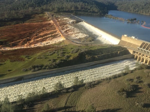 Water flows over the emergency spillway (background) at Lake Oroville on January 11, 2017, as the main spillway (foreground) operates at limited capacity due to erosion.